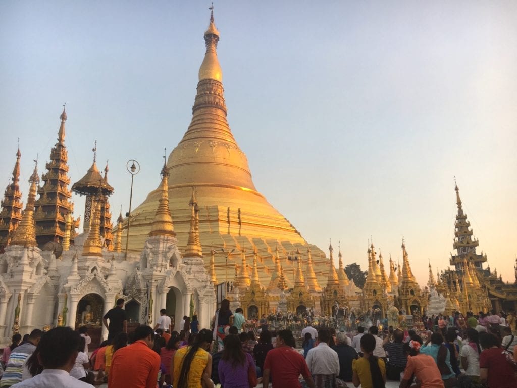 Shwedagon Pagoda at sunset with Buddhists Praying