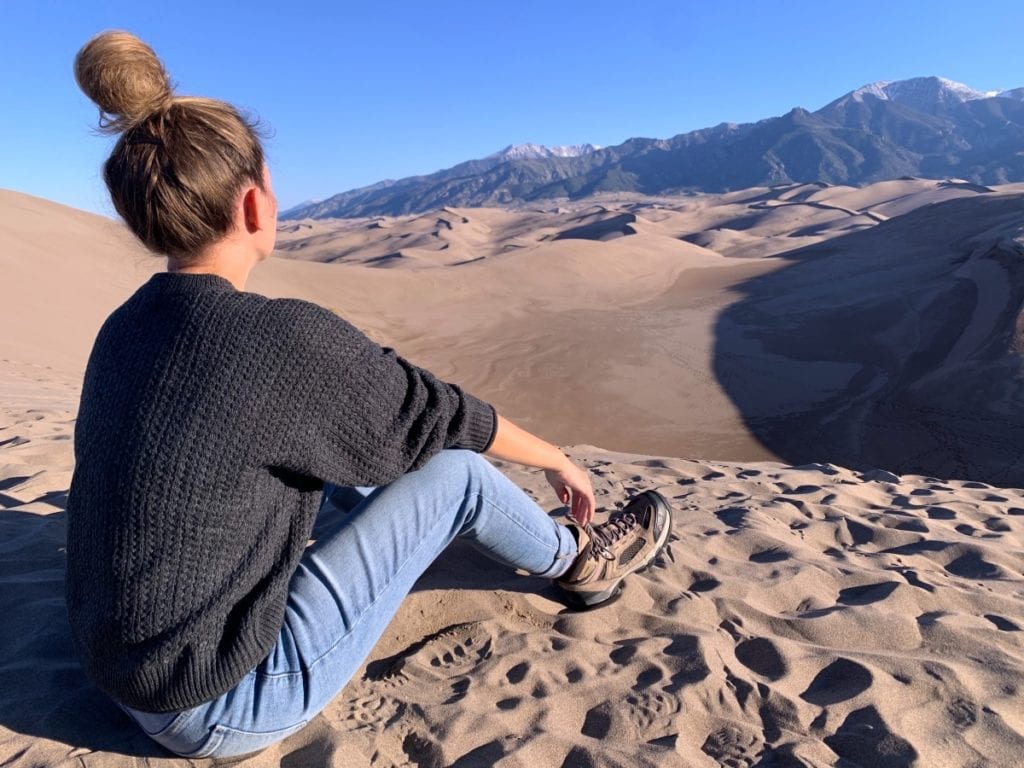 Colorado Road Trip - Lauren sitting a top the sand dunes